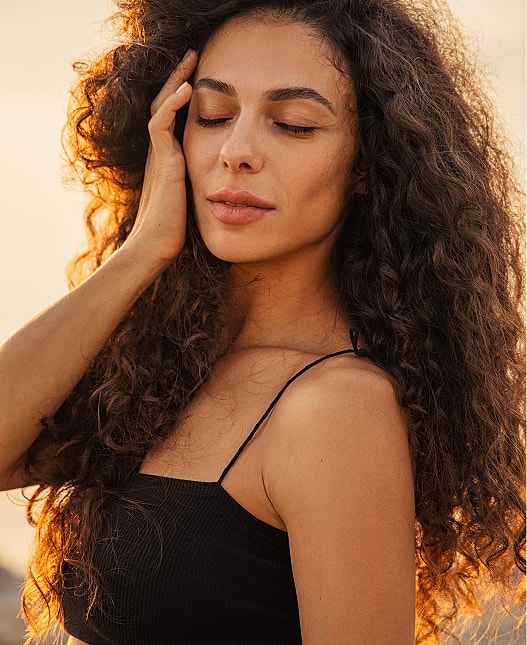 Rancho Santa Margarita Med Spa model with curly hair in sunset light.