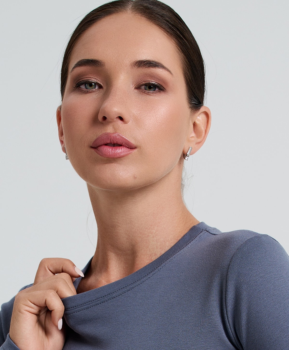 Woman with makeup in casual gray shirt.
