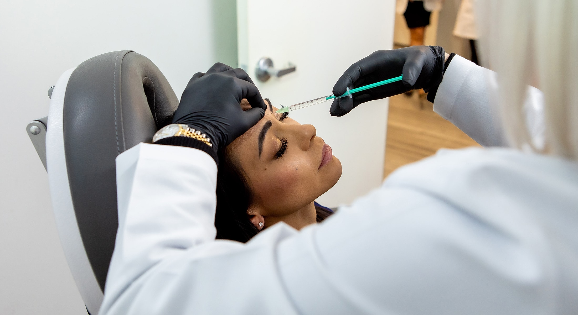 Injecting cosmetic treatment in patient’s forehead.