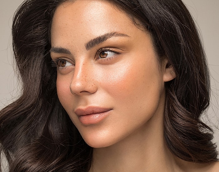 Woman with glowing skin and wavy hair.